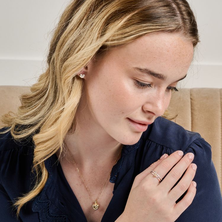 A model wears gold Puffy Heart Necklace and heart earrings from Lulu and Boo. 