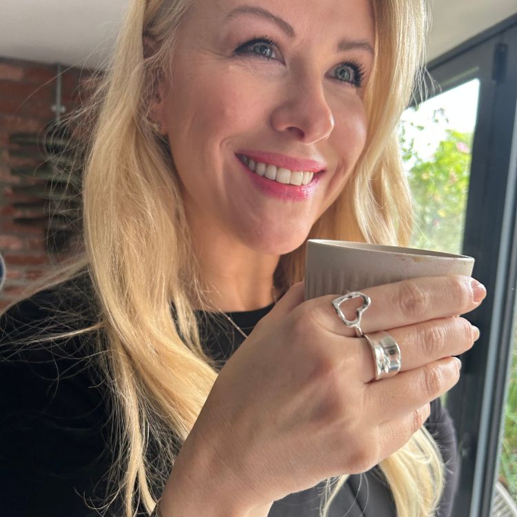 A hand wearing A silver heart ring from Lulu and Boo Jewellery.