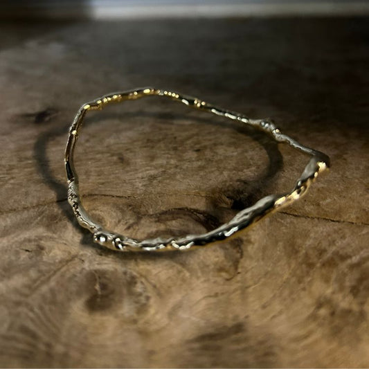 A Molten Wave 9ct Gold Bangle from Lulu and Boo Jewellery.